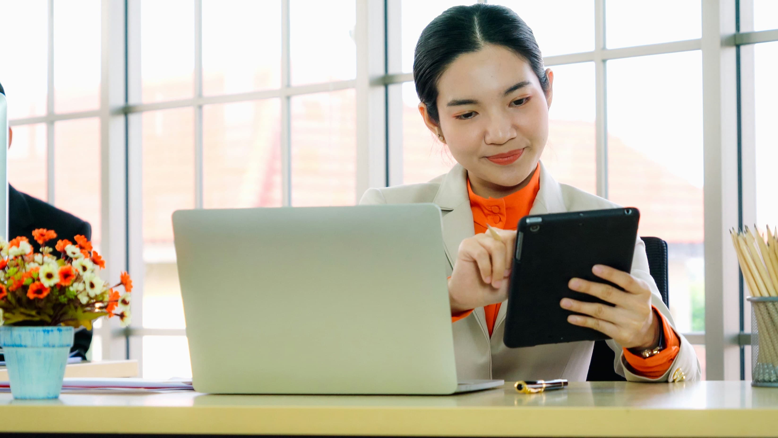A team member reviewing information on a tablet at her desk